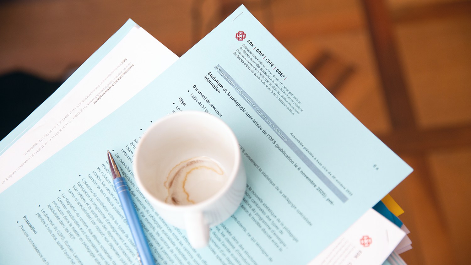 Une tasse de café vide et un stylo à bille sur plusieurs documents