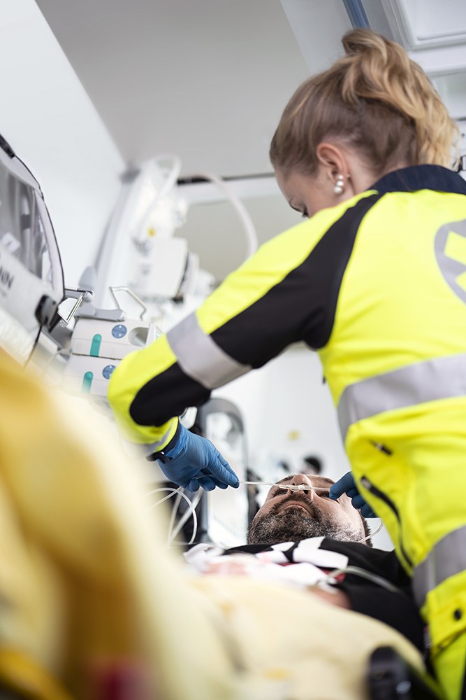 Eine Rettungssanitäterin verarztet einen Mann im Krankenwagen