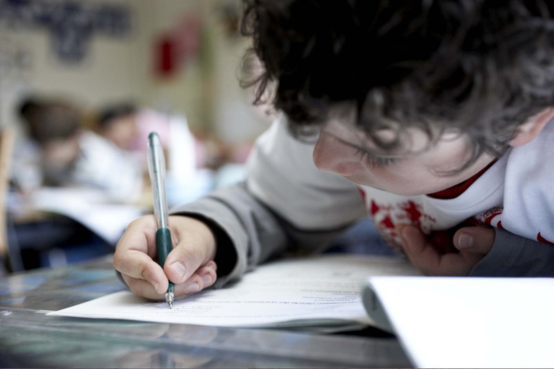 Un bambino concentrato scrive su un quaderno